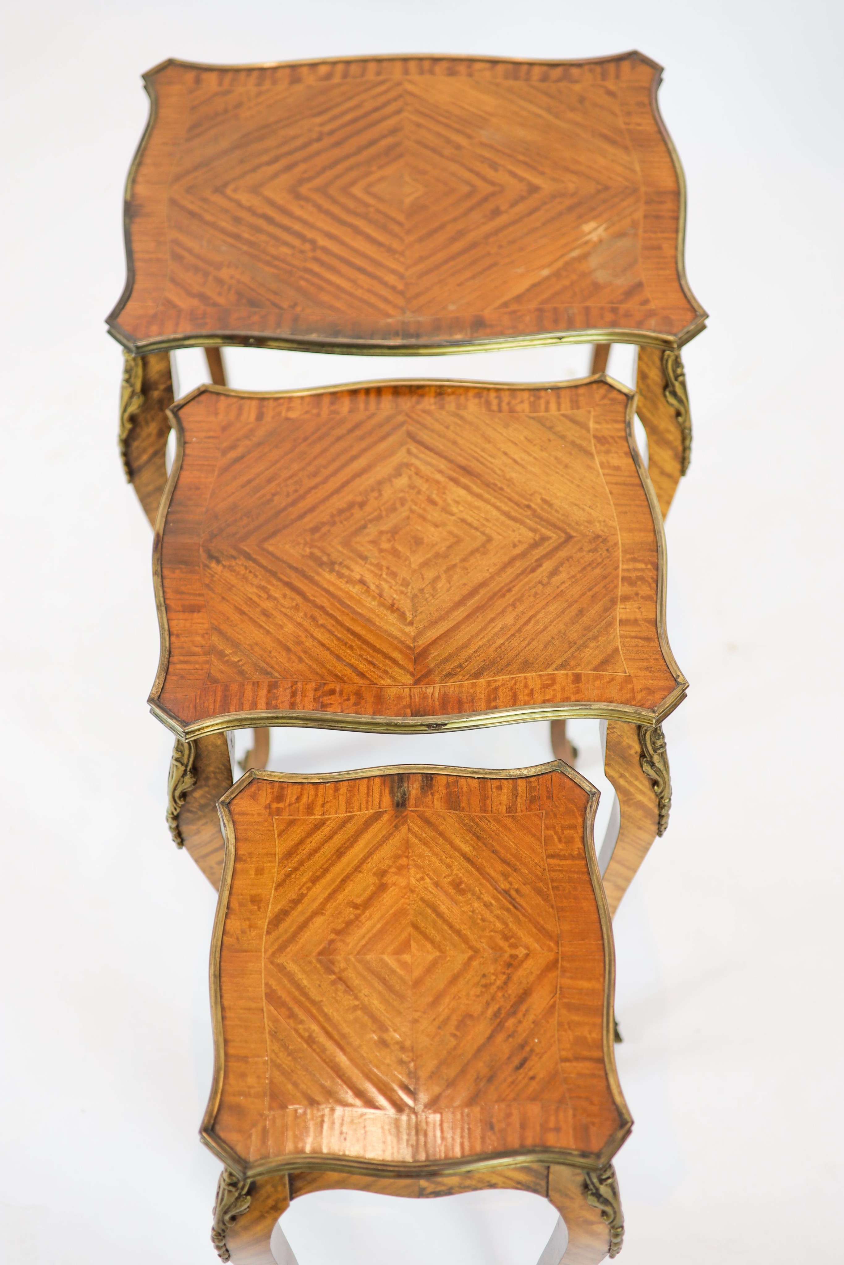 A nest of three Louis XV style ormolu mounted banded kingwood tables, with serpentine sides, on cabriole legs, width 51cm, depth 41cm, height 59cm